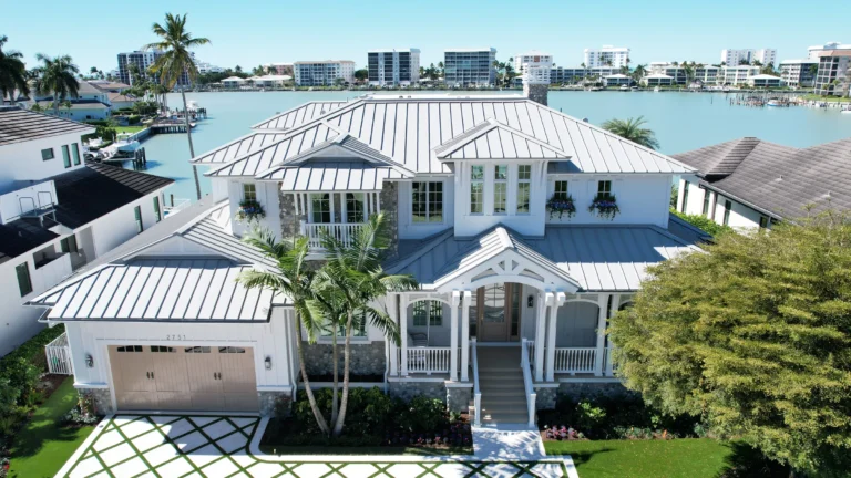 Front aerial view of waterfront Naples Florida residence featuring a standing seam metal roof system.