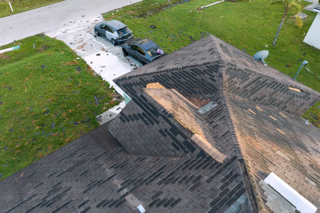 Wind-damaged asphalt shingle roof in Southwest Florida showing missing shingles after a severe storm.